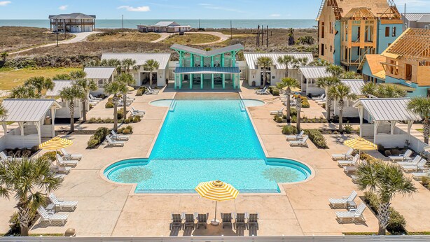A resort with a central pool, lounge chairs, and a view of the ocean. - Resort Style Pools, Sleeps 2,  Golf Cart Boardwalk to the Beach (Port Aransas)