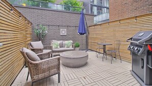 An outdoor patio with wicker furniture, a round table, and a grill. - Luxury Townhouse in Downtown Toronto (Toronto)