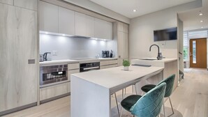 A modern kitchen with a central island, built-in appliances, and a flat-screen TV mounted above the sink. - Luxury Townhouse in Downtown Toronto (Toronto)