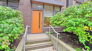 A modern building with a brick facade, a wooden staircase with metal railings, and a door with a glass panel. - Luxury Townhouse in Downtown Toronto (Toronto)