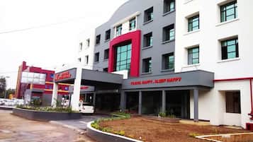 Un hotel con fachada moderna, múltiples ventanas y un llamativo esquema de color rojo y gris.
