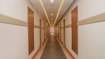 Un pasillo largo y estrecho con puertas a ambos lados, que conduce a una habitación luminosa al final.