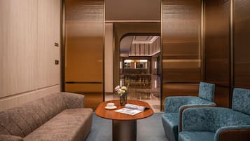 Un moderno vestíbulo de hotel con un mostrador de recepción de madera, dos sofás y un jarrón con flores.