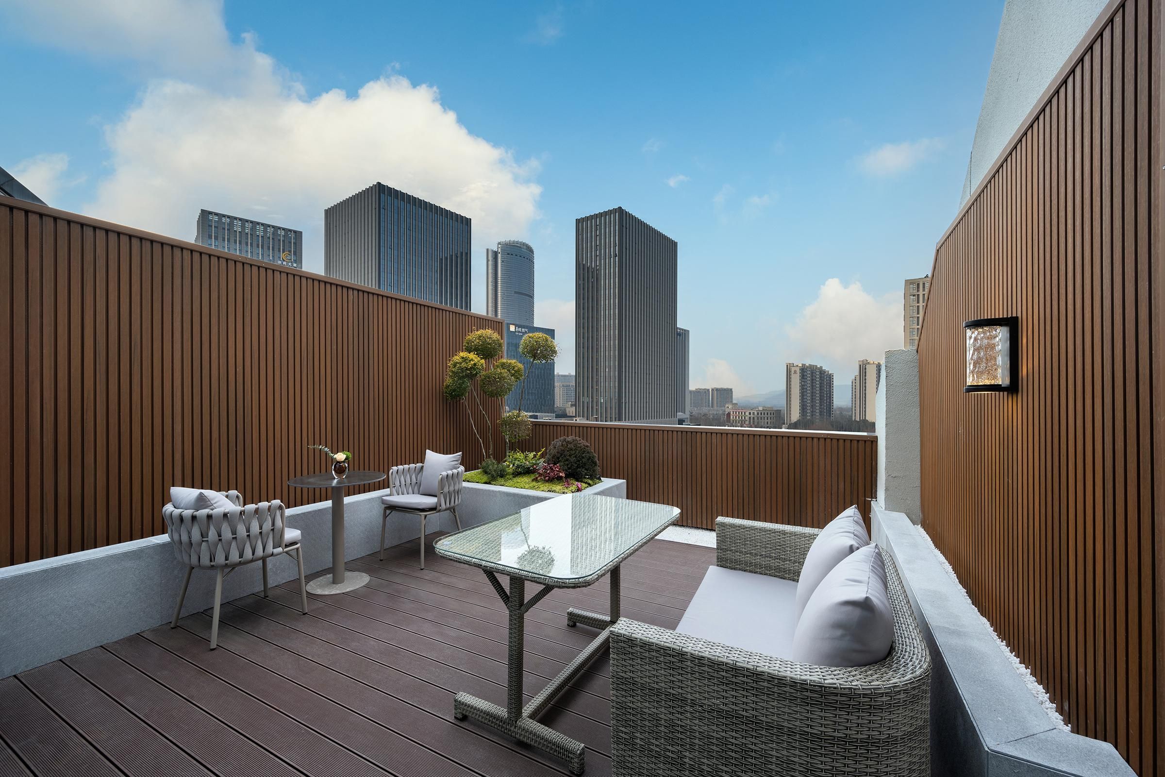 A rooftop terrace with a wooden deck, seating area, and a table.