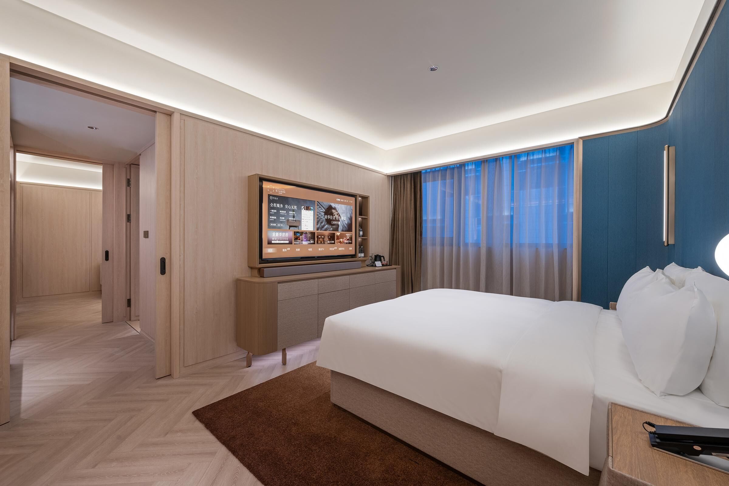 Ein Hotelzimmer mit einem großen Bett, einem Flachbildfernseher, einem Schreibtisch und Blick ins Freie.