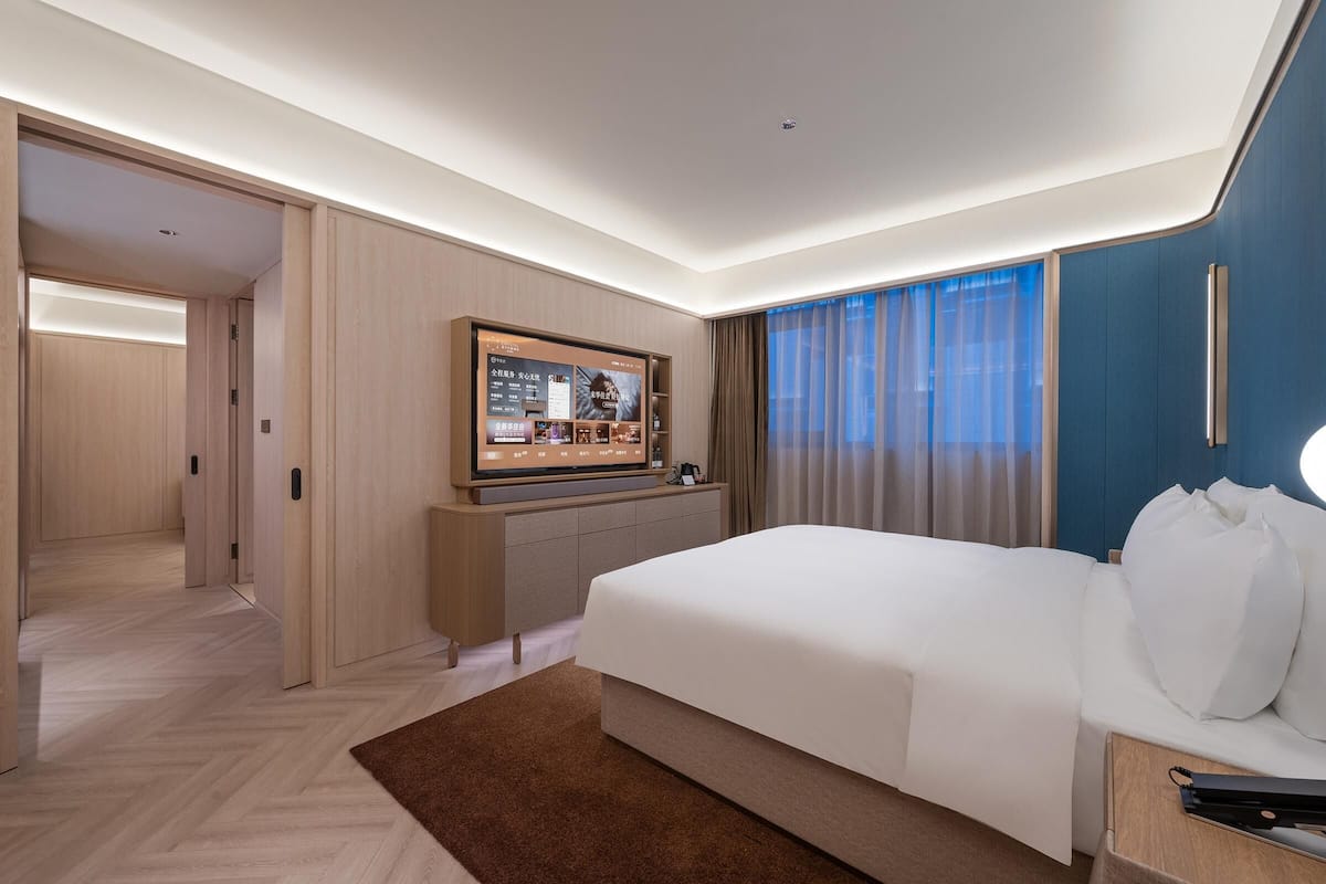 A hotel room with a large bed, a flat-screen TV, a desk, and a view of the outside.
