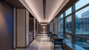 A modern hotel corridor with a marble floor, wooden paneling, and large windows offering a view of the city. - Crystal Orange Hotel Nanjing Southeast University (Nanjing)