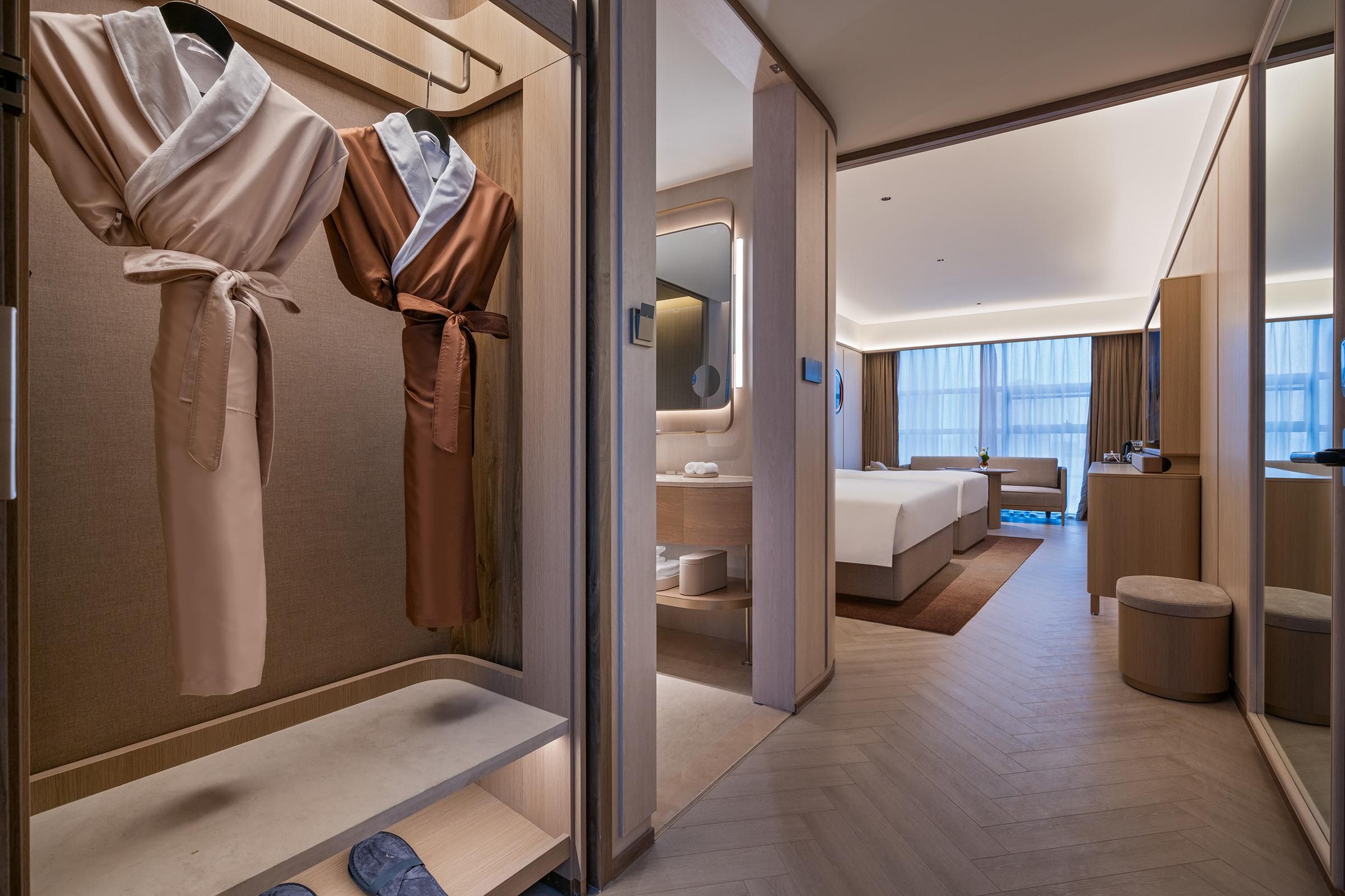 Habitación de hotel moderna con vestidor, cama, baño y vistas a la ciudad.