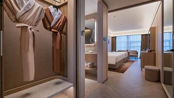 Habitación de hotel moderna con vestidor, cama, baño y vistas a la ciudad.
