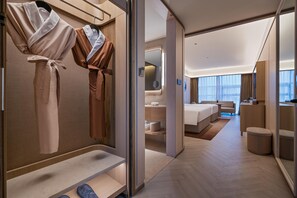 Une chambre d’hôtel moderne dotée d’un dressing, d’un lit, d’une salle de bain et offrant une vue sur la ville.