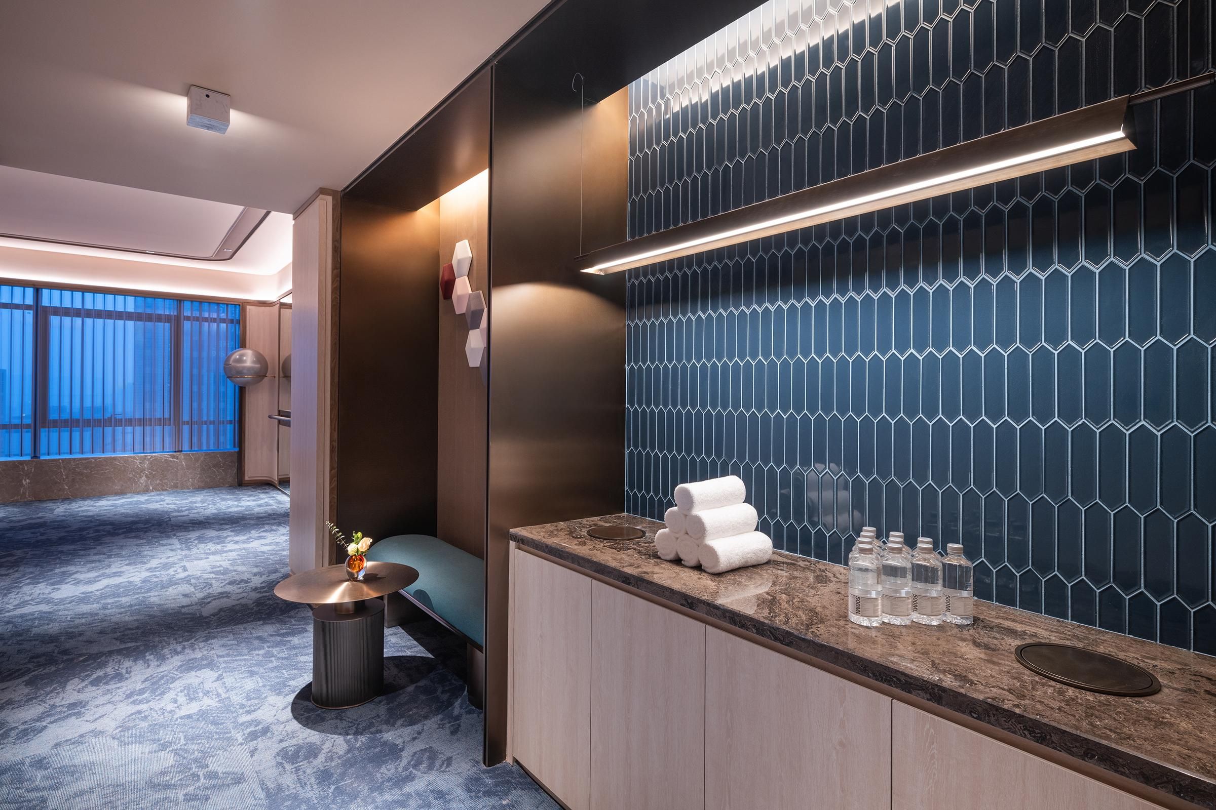 Un baño de hotel moderno con tocador, barra para toallas y pared con estampado azul.
