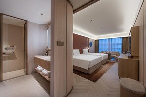 A modern hotel room with a large bed, a separate seating area, a bathroom with a vanity, and a view of the city through large windows. - Crystal Orange Hotel Nanjing Southeast University (Nanjing)