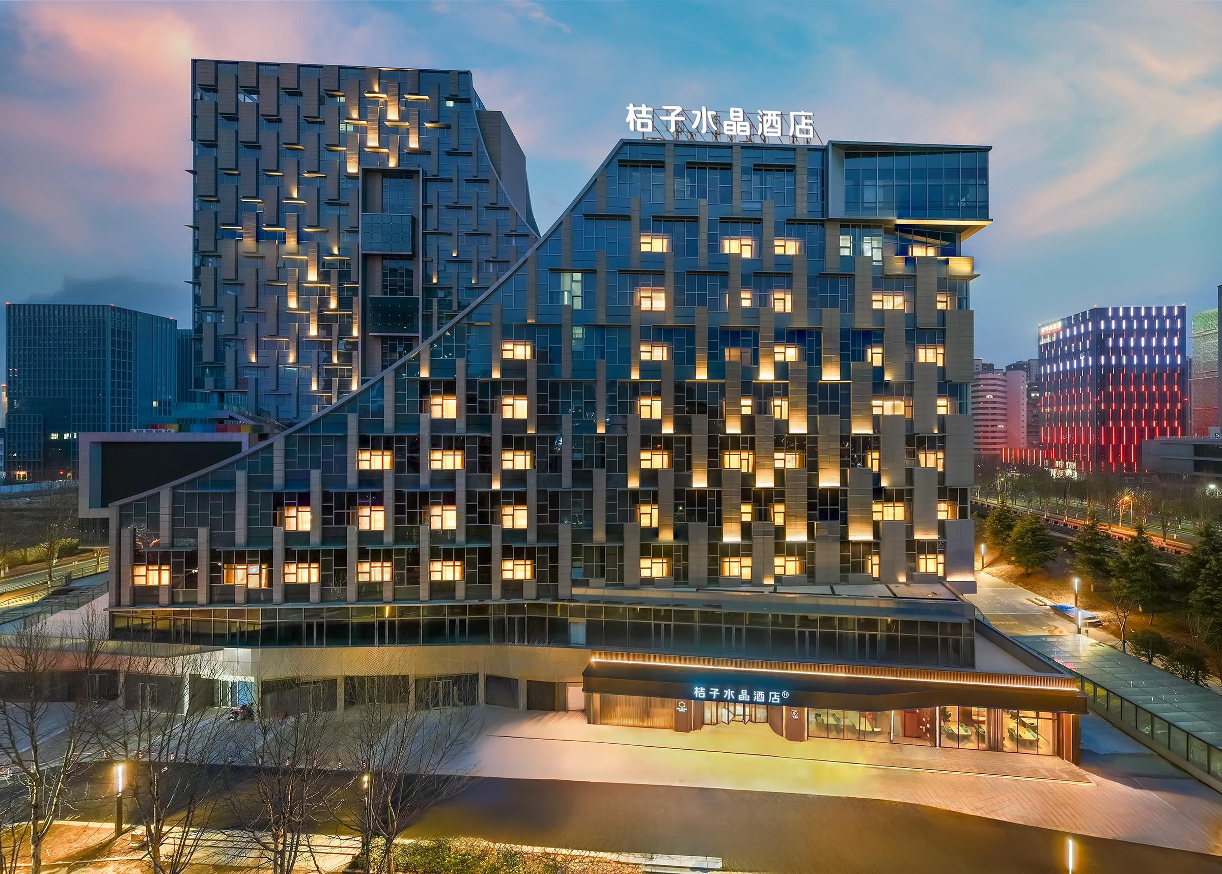 A modern hotel with a distinctive geometric facade, multiple floors, and a prominent signage at the top.