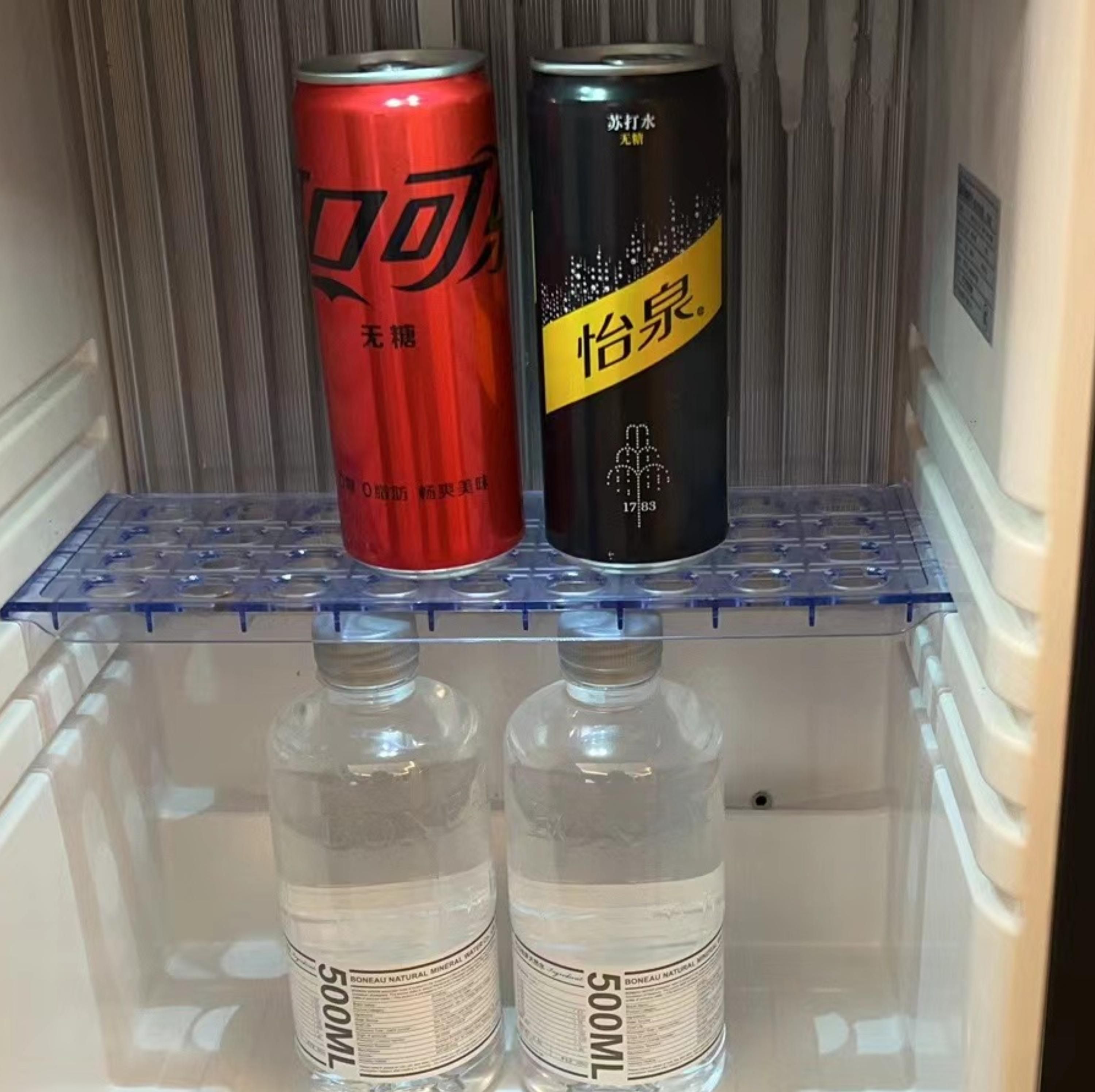 Un réfrigérateur contenant deux canettes et deux bouteilles d’eau.