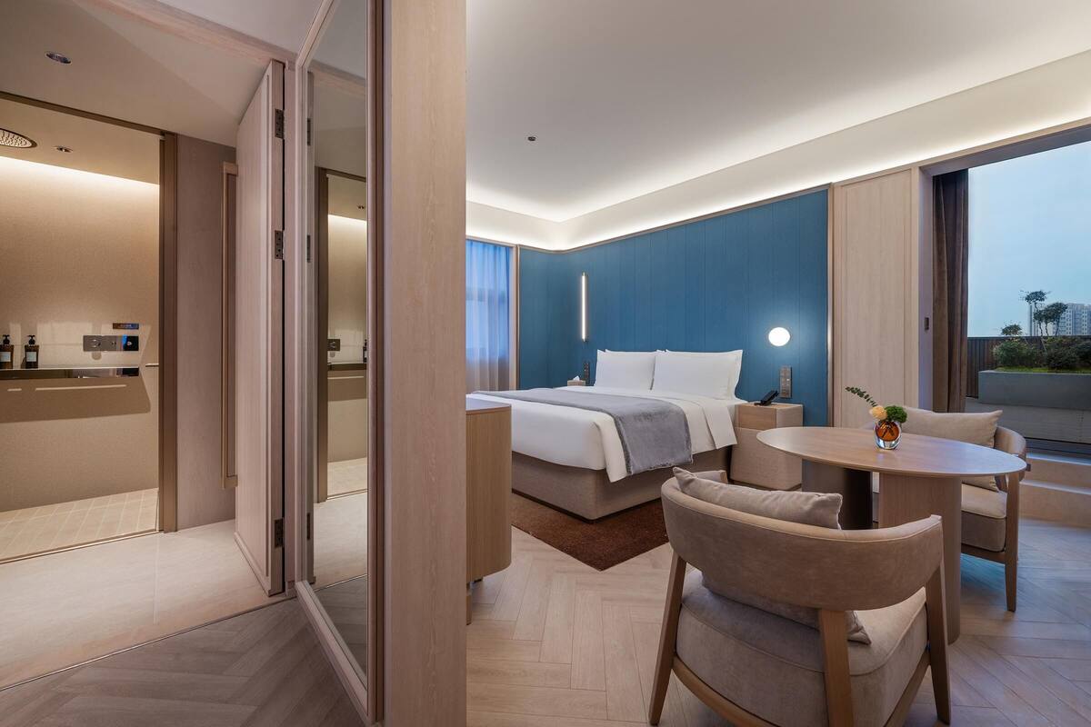 Ein modernes Hotelzimmer mit Bett, Schreibtisch, Stuhl und Blick auf die Stadt.