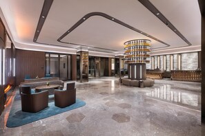 Un hall d’entrée spacieux avec un bar central, des espaces aménagés pour s’asseoir et un sol en marbre poli.