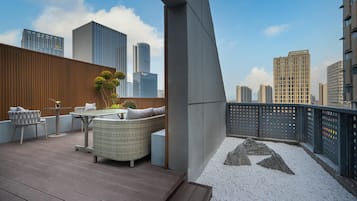 Terraço no telhado com área de estar moderna ao ar livre, vista do horizonte da cidade e uma rocha decorativa.