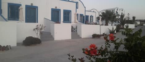 A white building with blue trim and a staircase leading to a door.