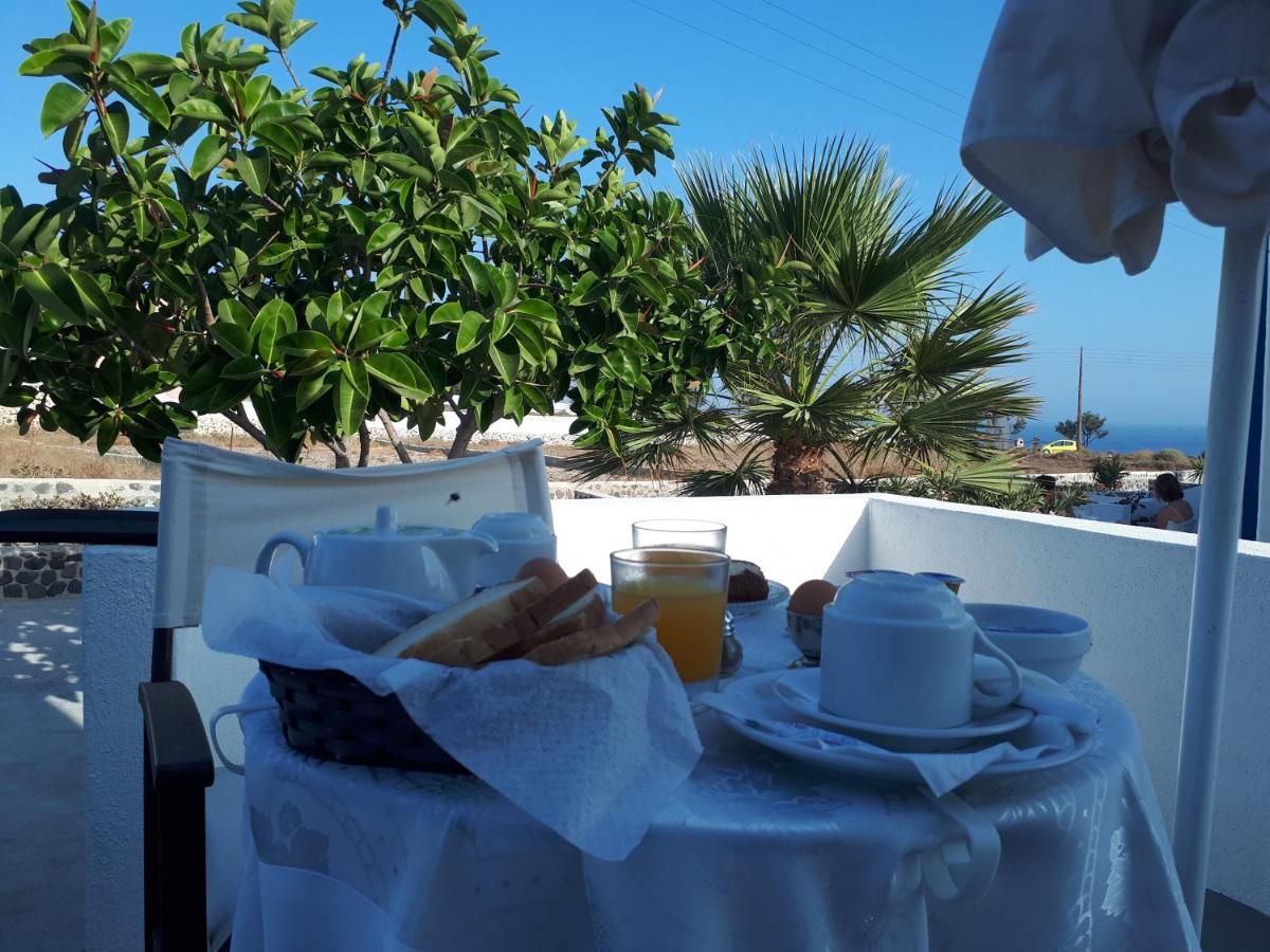 A breakfast setup on a balcony with a table, a basket of bread, a glass of orange juice, and a cup.