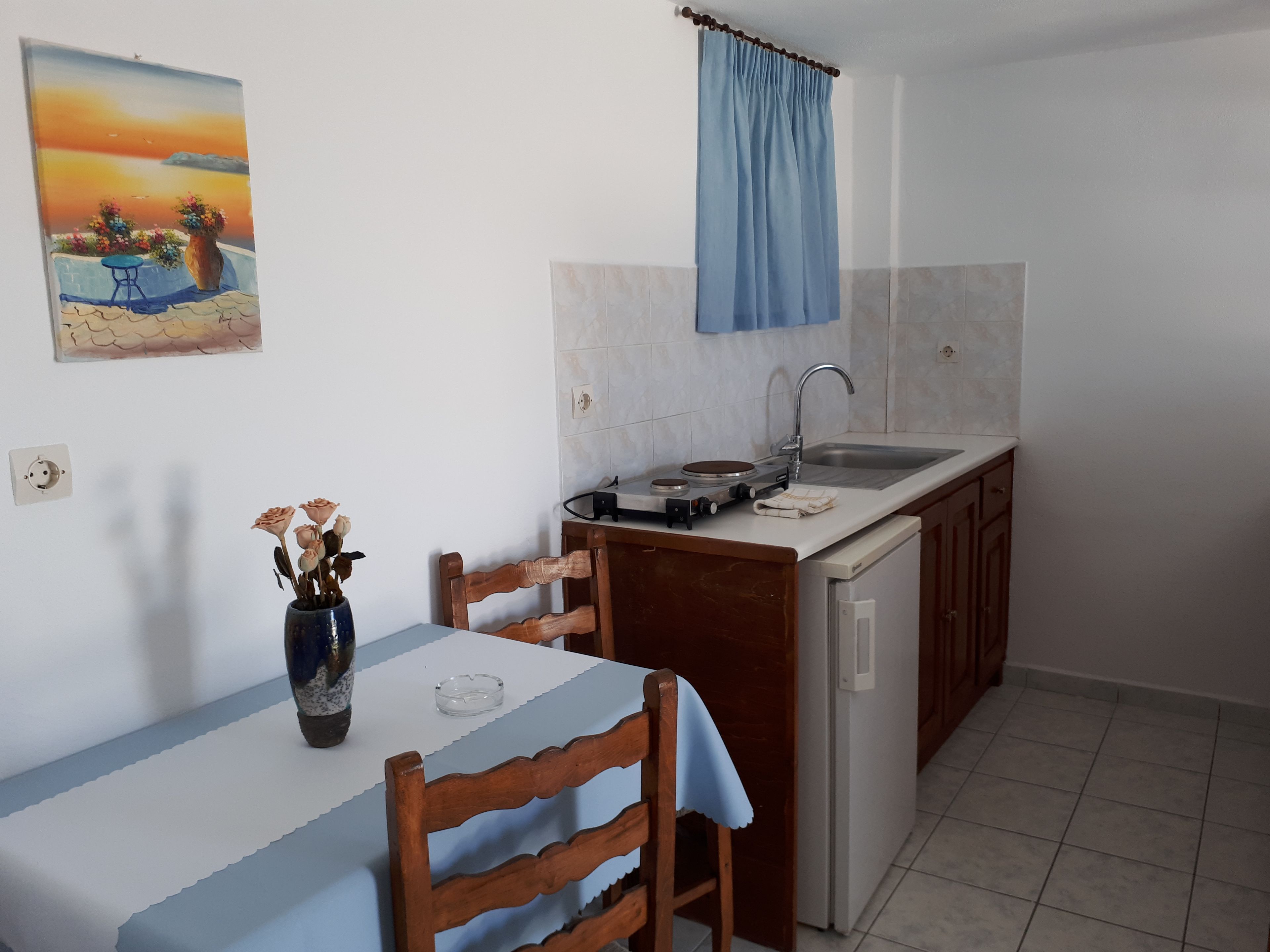 A small kitchen with a dining table, chairs, a sink, and a stove.