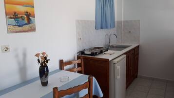 A small kitchen with a dining table, chairs, a sink, and a stove.