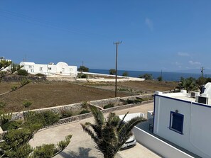 A coastal property with white buildings, a paved area, and a view of the sea. - Hotel Paradisos Oia (Santorini)