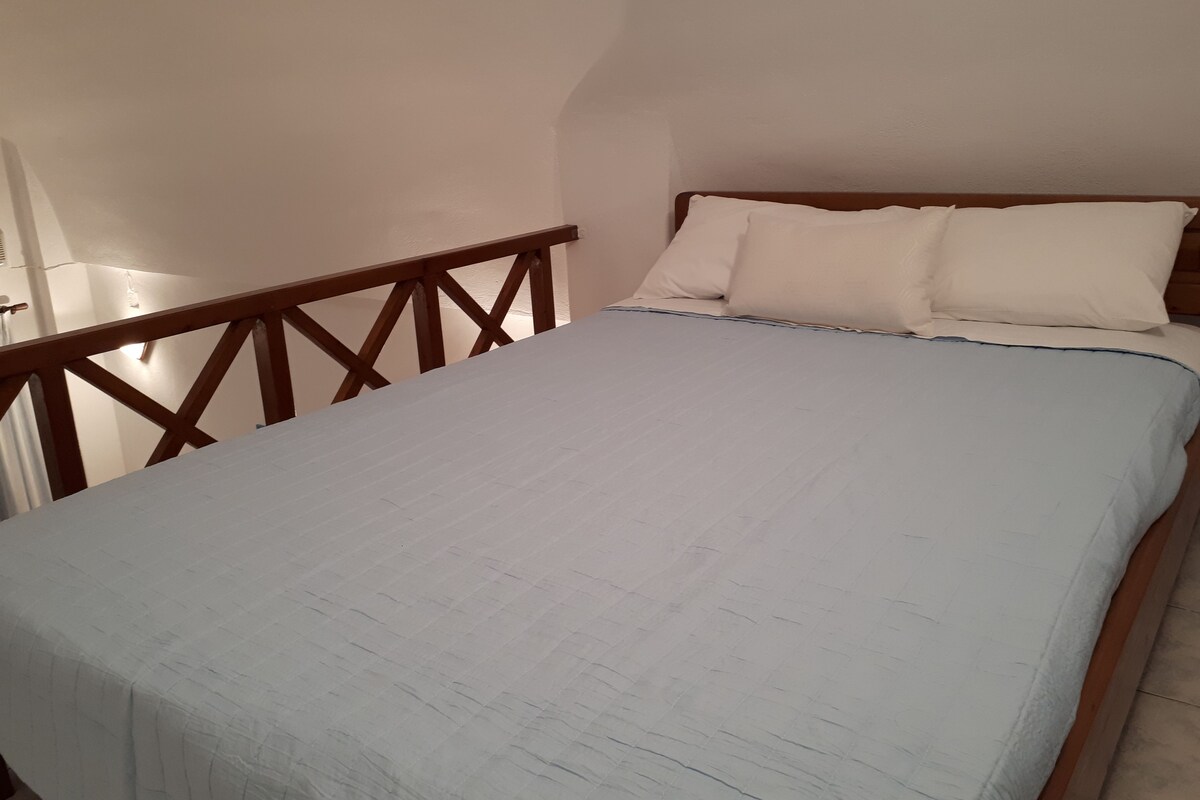 A bedroom with a bed, wooden headboard, and a white wall.