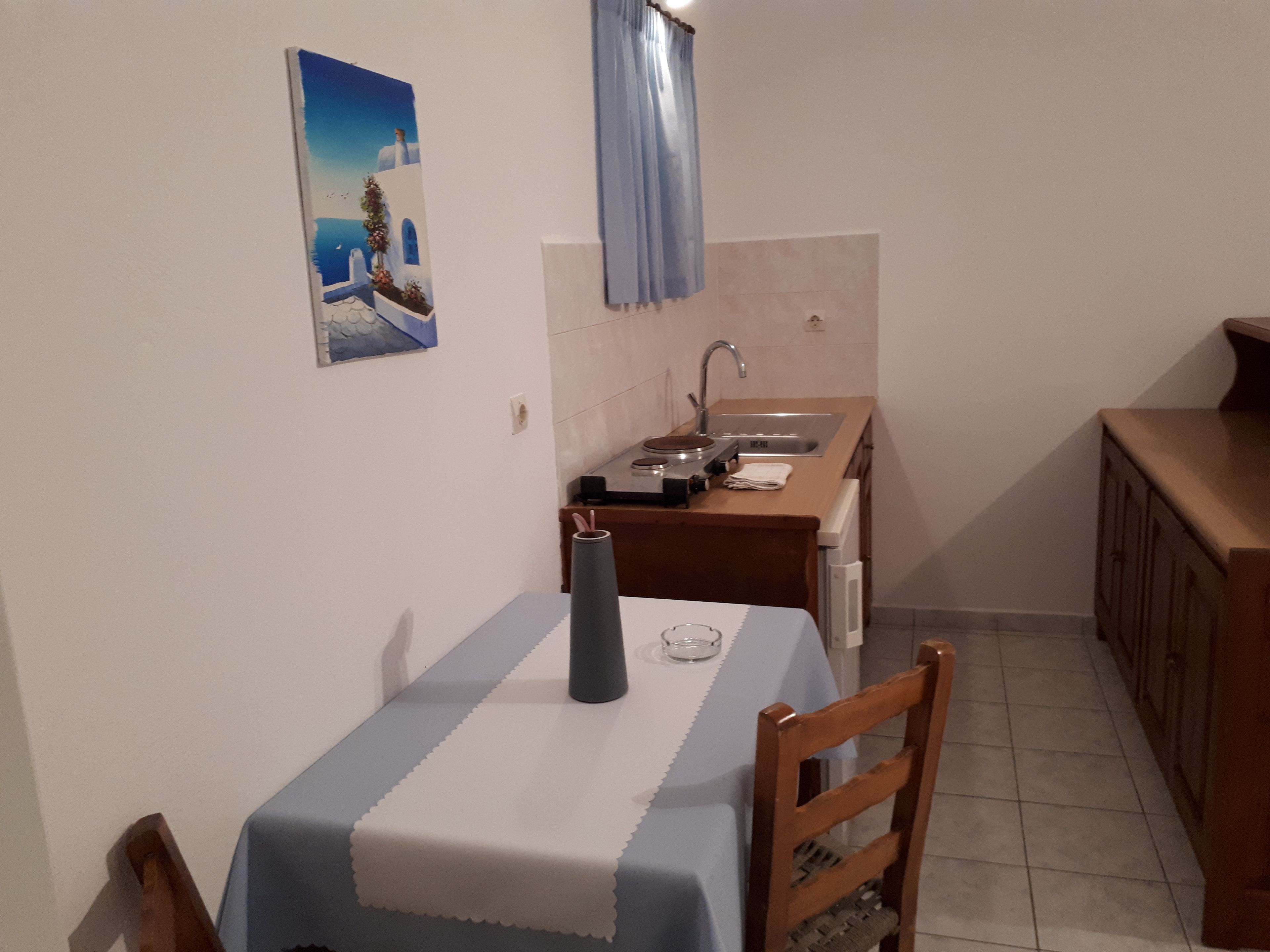 Una cocina pequeña con una mesa, sillas, un lavamanos y un armario.