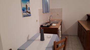 Una cocina pequeña con una mesa, sillas, un lavamanos y un armario.