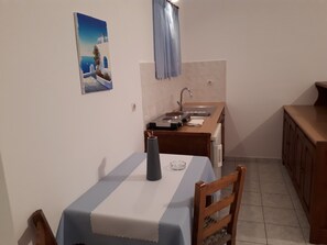 A small kitchen with a table, chairs, a sink, and a cabinet.