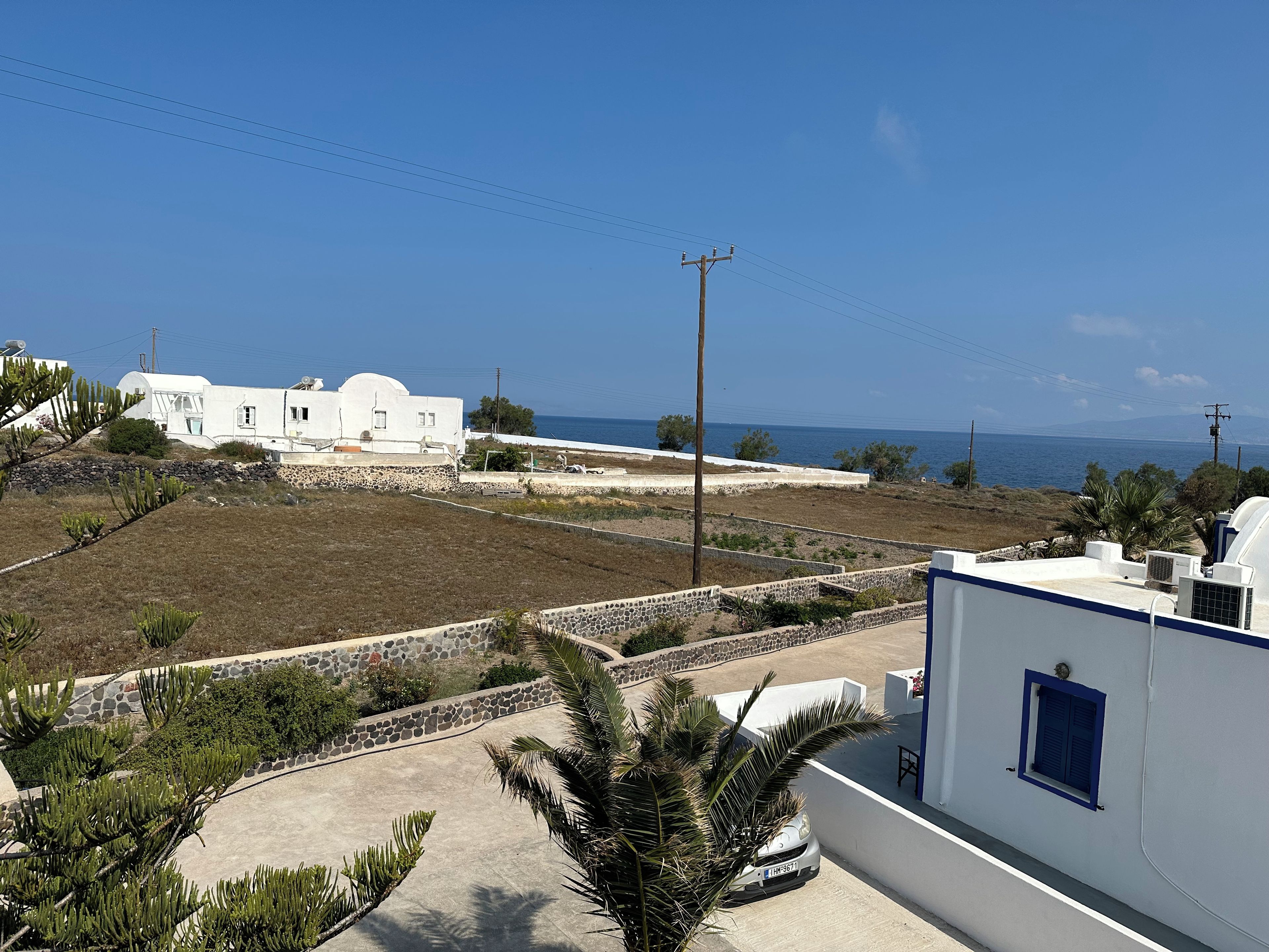Una propiedad costera con edificios blancos, un área pavimentada y vista al mar.