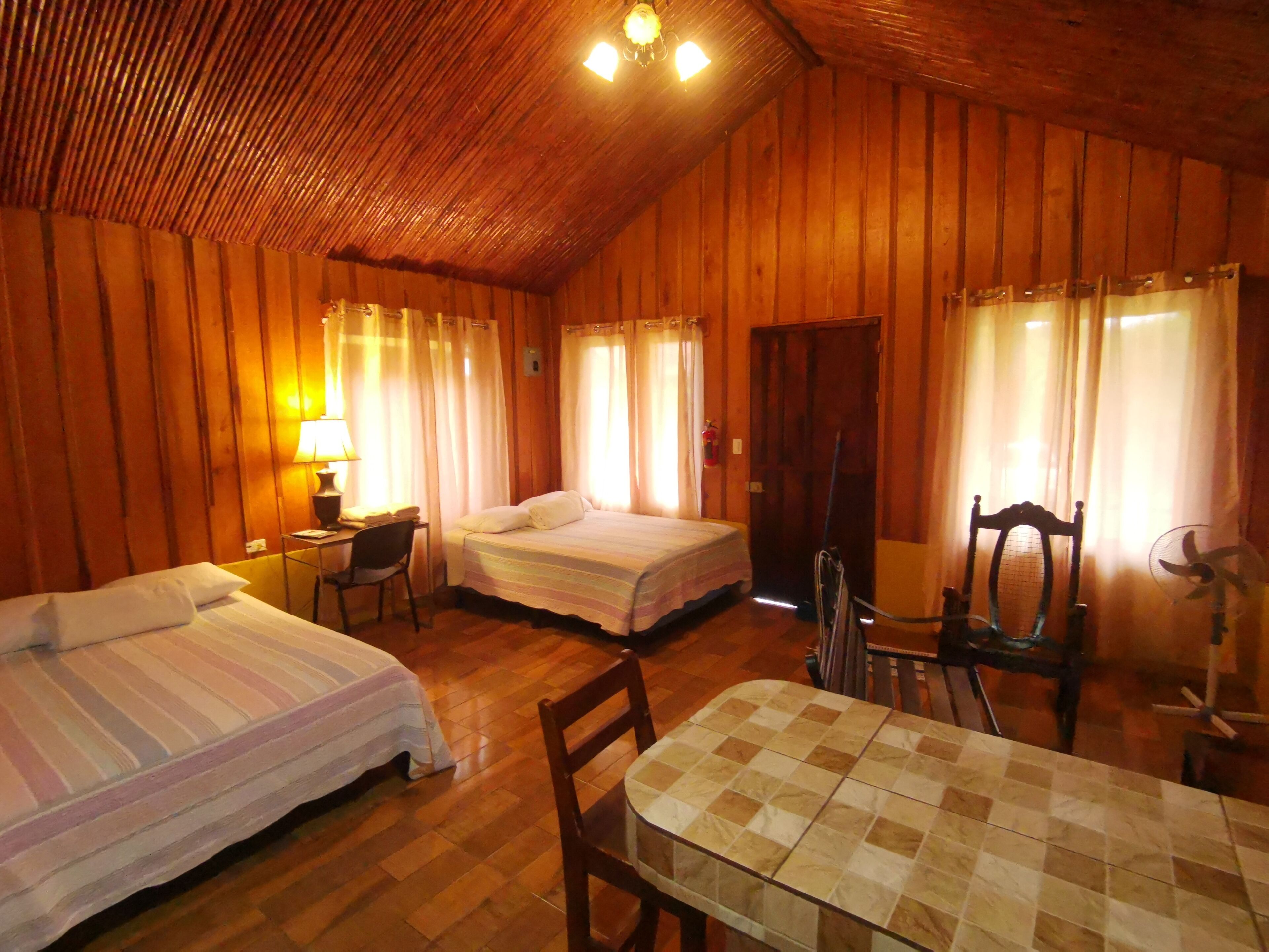 Um quarto aconchegante com duas camas, uma escrivaninha, uma cadeira e uma mesa.