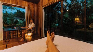 A room with a bed, a table, and a window with a view of trees. - Las Cabanas (Venecia)