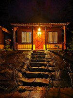 Una casa de madera con un gran portal, dos ventanas y una escalera que lleva a la entrada.