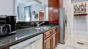 A modern kitchen with a built-in dishwasher, a coffee maker, a refrigerator, and a wine rack. - Historic Savannah Condo, Sleeps 6, Pool, Dogs Ok (Savannah)