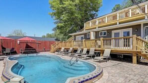 A swimming pool with a wooden deck, lounge chairs, and a covered area with a red roof. - Historic Savannah Condo, Sleeps 6, Pool, Dogs Ok (Savannah)