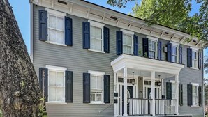 A two-story building with a porch, multiple windows, and a brick foundation. - Historic Savannah Condo, Sleeps 6, Pool, Dogs Ok (Savannah)