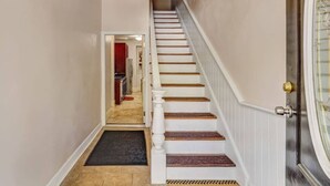 A hallway with a staircase leading to a room, a door with a glass panel, and a red object in the background. - Historic Savannah Condo, Sleeps 6, Pool, Dogs Ok (Savannah)