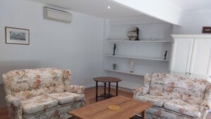 Un salon avec deux canapés à motifs floraux, une table basse en bois, une petite table ronde et un meuble blanc.