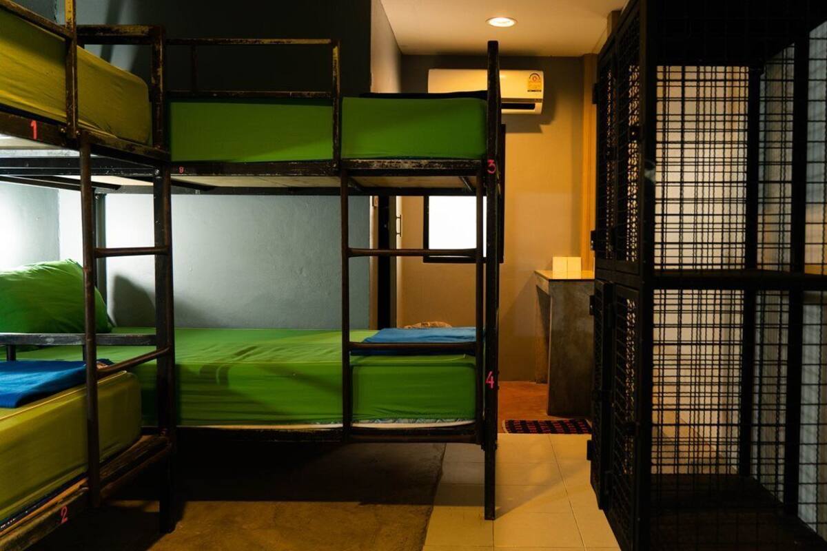 A dormitory room with bunk beds, a window, and a traditional-style door.