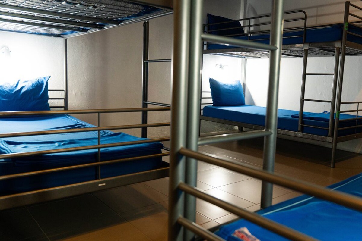 A bunk bed room with metal railings and blue bedding.