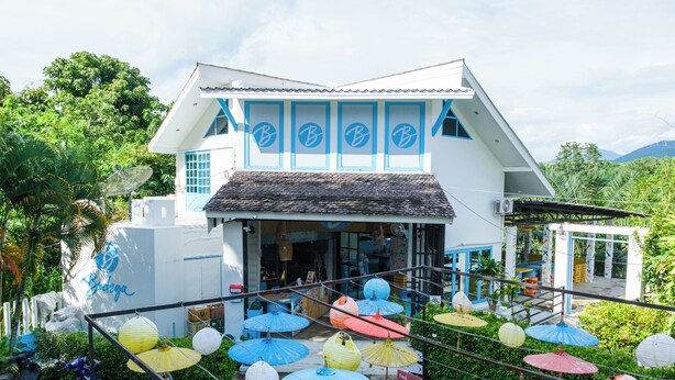 A white building with blue accents and a sloped roof. - Bodega Pai (Pai)
