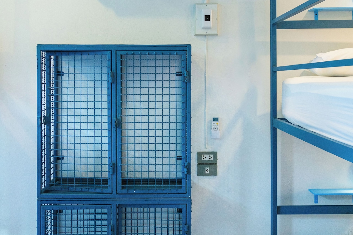 A room with bunk beds, an air conditioning unit, and a blue metal gate.