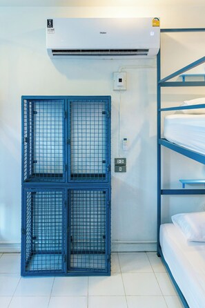 A room with bunk beds, an air conditioning unit, and a blue metal gate. - Bodega Pai (Pai)