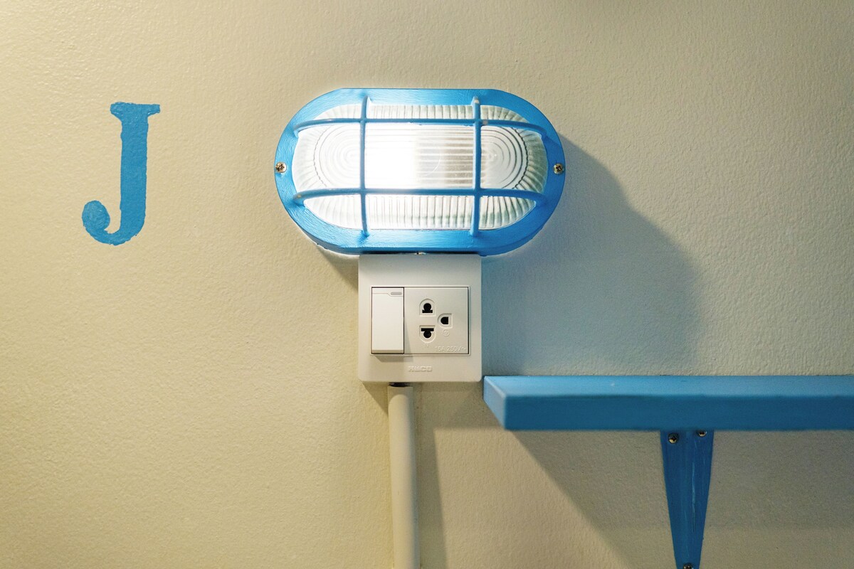 Eine wandmontierte Klimaanlage mit blauem Rahmen, eine Steckdose und ein blaues Regal.