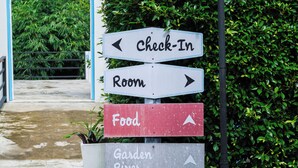 Un indicador direccional con flechas que señalan 'Check-In Room', 'Food' y 'Garden River'.