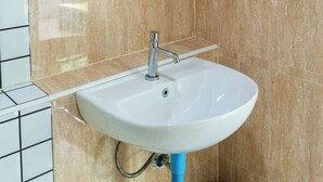 A bathroom with a white sink, a mirror, and a black trash bin. - Bodega Pai (Pai)