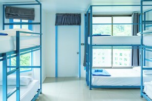 Ein Zimmer mit Etagenbetten, einem fensterbelaubten Fenster und einer Tür.