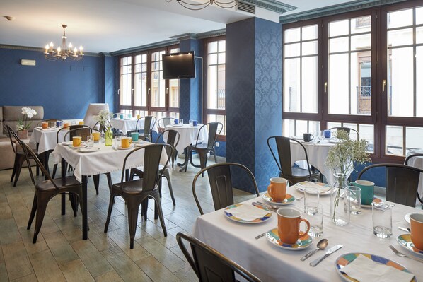 A dining area with tables set for meals, chairs, and a chandelier. - Iraipe Ongi Hotel (Oñati)
