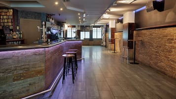 A bar area with a counter, stools, and a bookshelf with various items.